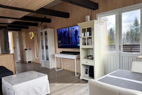 a living room with a flat screen tv on the wall at Spacious Summerhouse with Hot Tub & Garden in Selfoss
