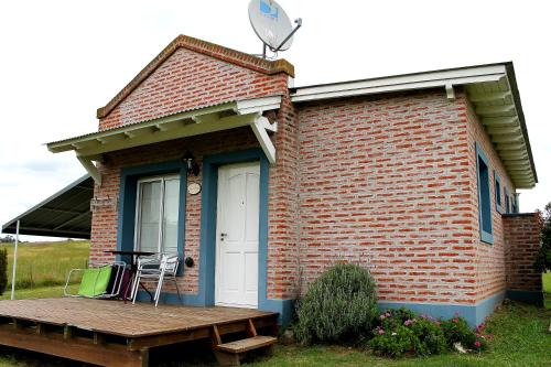 a small brick house with a porch and a deck at Cabañas Arcángeles de Tandil in Tandil