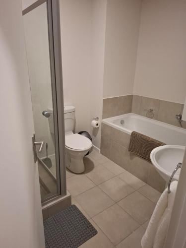 a bathroom with a toilet and a tub and a sink at Bliss Ballito Apartment in Ballito