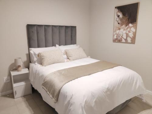 a bedroom with a white bed with a gray headboard at Bliss Ballito Apartment in Ballito