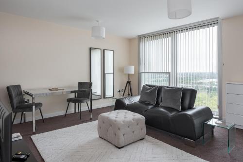 a living room with a black leather couch and a table at City Stay Apartments - Hub in Milton Keynes