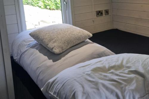 a bed in a room with a pillow on it at Glamping Hut - Sleeps 2 hot tub & parking in Garthbeibio