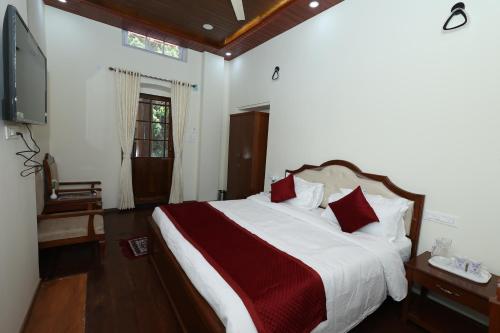 a bedroom with a large bed with red pillows at KSTDC Hotel Mayura Sudarshan ,Ooty in Ooty