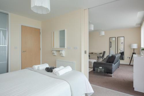 a bedroom with a white bed and a chair at City Stay Apartments - Hub in Milton Keynes