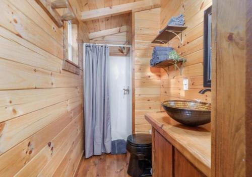 a bathroom with a sink and a wooden wall at Copperhead Cabin- Hocking Hills Hot Tub Games in Logan