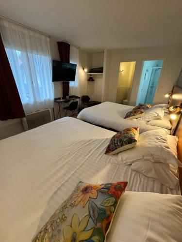 ein Hotelzimmer mit drei Betten und einem Fernseher in der Unterkunft Cit'Hotel Capricorne in Vendôme