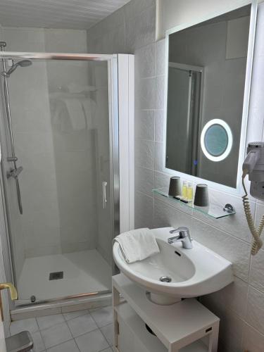 ein weißes Badezimmer mit Dusche und Waschbecken in der Unterkunft Cit'Hotel Capricorne in Vendôme