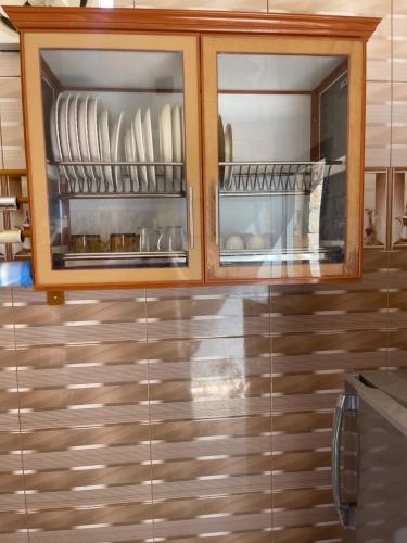 a kitchen with wooden cabinets with plates and dishes at Jabal Shams, the summit house in Misfāh