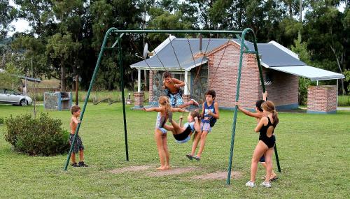 a group of children playing on a swing at Cabañas Arcángeles de Tandil in Tandil