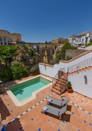 a swimming pool with two lounge chairs and a building at The Gorge House in Ronda