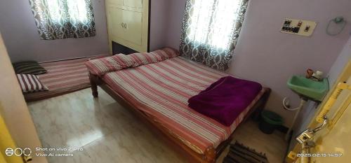 ティルヴァンナーマライにあるSHREE CHENDUR Residencyの紫色の枕が置かれたベッドのある小さな部屋