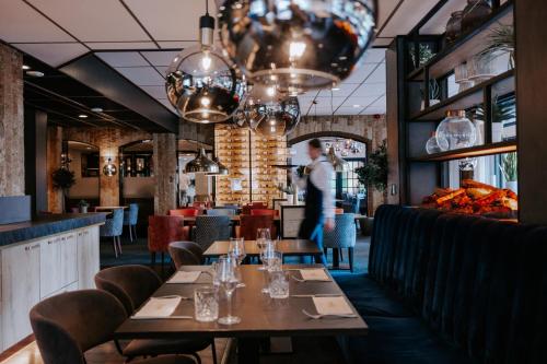 ein Esszimmer mit Tischen, Stühlen und Kronleuchtern in der Unterkunft Hotel De Oringer Marke Odoorn, nabij Emmen in Odoorn