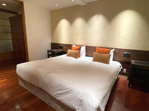 a bedroom with a large white bed with orange pillows at ISANA Resort in Ito