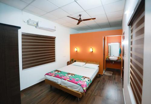 a bedroom with a bed with an orange wall at Penuel marari homesty in Mararikulam