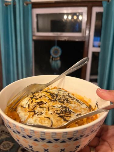 a person holding a bowl of food with a spoon at The Blue House in Pelling