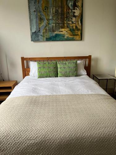 a bed with white sheets and green pillows at Large garden-view room, 20 min from Central London, in a stylish period property in Lee, with free parking and a friendly Jack Russell in London