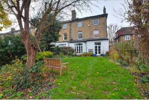 a bench sitting in the yard of a house at Large garden-view room, 20 min from Central London, in a stylish period property in Lee, with free parking and a friendly Jack Russell in London