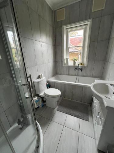 a bathroom with a tub and a toilet and a sink at Double room near Blackheath, 17 min from Central London, a stylish period property, with free parking in London