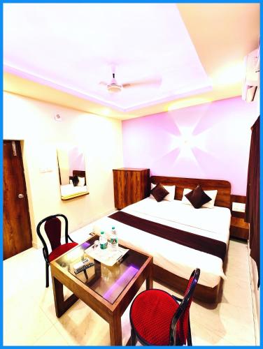 カタックにあるHotel Inn Blue Sagar -Lift & Parking Facilities - Room Service & Restaurant - Garden - free wifi - Boutique Collection and Unique Room Decoration # Best Hotel In Puriのベッドとテーブルと椅子のあるホテルの部屋