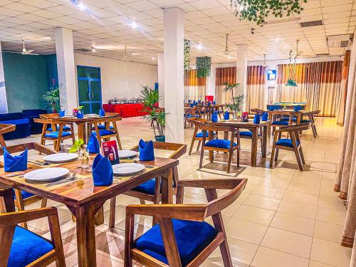 a dining room with wooden tables and blue chairs at Oasis Ayurveda Resort Wadduwa in Wadduwa