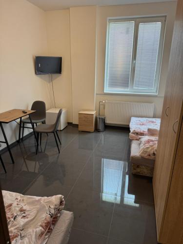 a room with three beds and a table and a tv at Ubytovanie Nitra in Nitra