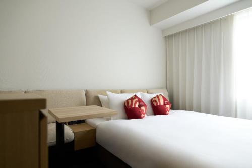 a bedroom with a bed with red pillows and a table at OMO3 Tokyo Akasaka by Hoshino Resort in Tokyo