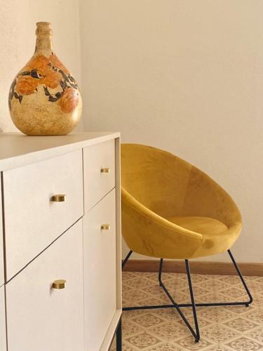 a yellow chair sitting next to a cabinet with a vase at Podere Ainzara in Montemerano