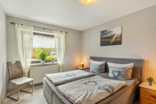a bedroom with a bed and a chair and a window at Ferienwohnung Fischer in Heringhausen