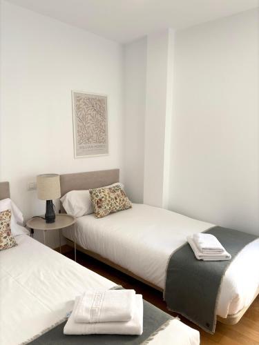 a bedroom with two beds and a table with a lamp at The Zentral Suites & Apartments in Seville
