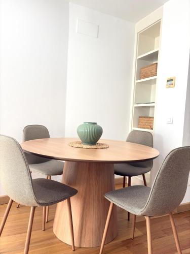 a wooden table with chairs and a vase on top at The Zentral Suites & Apartments in Seville