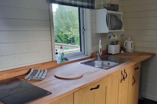 a kitchen counter with a sink and a window at Glamping Hut - Sleeps 2 hot tub & parking in Garthbeibio