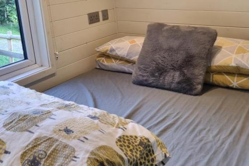 a bedroom with two beds and a window at Glamping Hut - Sleeps 2 hot tub & parking in Garthbeibio