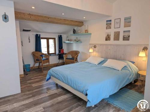 a bedroom with a blue bed and a table and chairs at La maison millesime in La Caunette