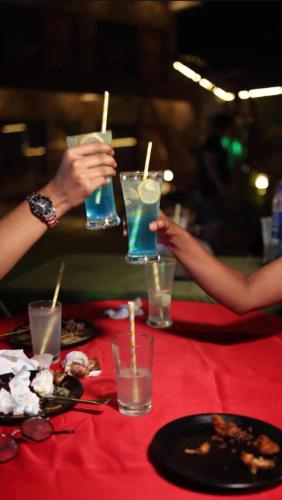 two people holding drinks on a red table with plates of food at Be delight corbett in Rāmnagar