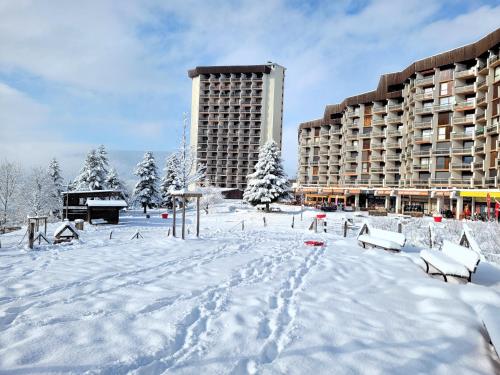 a snow covered parking lot in front of a building at Lumineux studio vue montagne cote 2000 in Villard-de-Lans