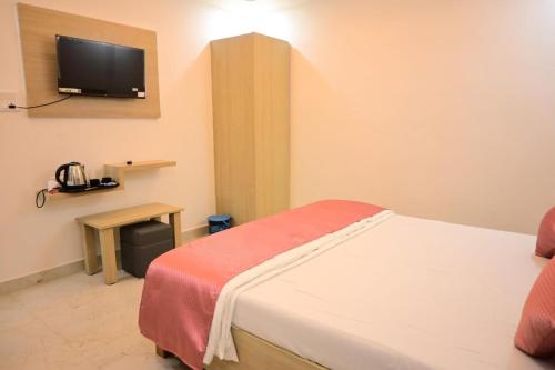Una habitación de hotel con una cama y un televisor. en Hotel Kanha Inn Ayodhya, en Ayodhya