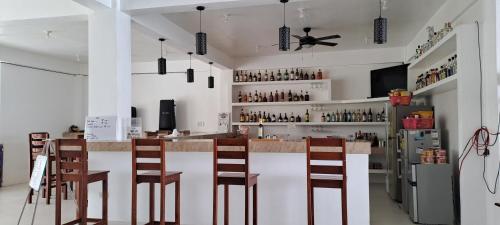 a kitchen with a bar with chairs and a refrigerator at Chilly Beach Resort Palawan in Aborlan