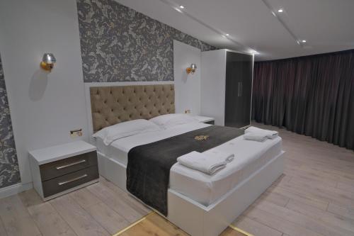a bedroom with a large bed and a night stand at 3D Hotel in Tirana