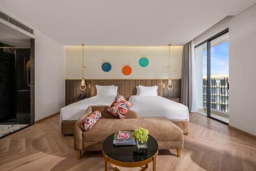 a hotel room with a bed and a couch at Wyndham Hoi An Royal Beachfront Resort & Villas in Hoi An
