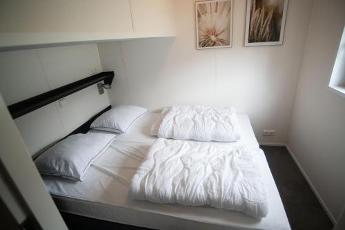 a bedroom with a bed with white sheets and pillows at De Bijsselse Enk, Noors chalet 19 in Nunspeet