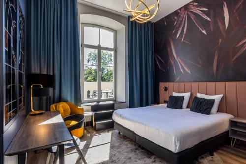 a hotel room with a bed and a desk at MERICI Hotel Sittard in Sittard