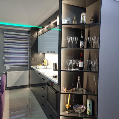 a kitchen with black shelves with wine glasses at Ramonda Smještaj in Tuzla