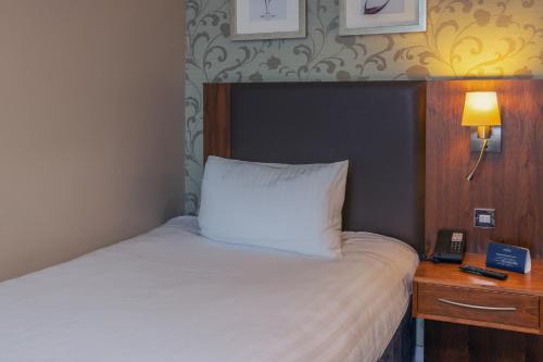 a bedroom with a bed and a night stand with a phone at Gloucester Robinswood Hotel, BW Signature Collection in Gloucester