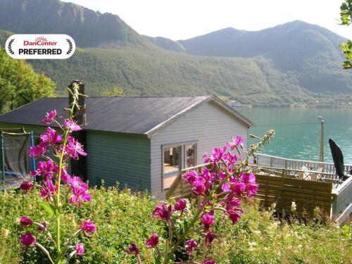 a house with purple flowers in front of a lake at 10 person holiday home in Kaldfarnes-By Traum in Sifjord