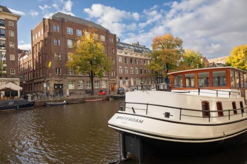 a boat is docked on a river in a city at Canal Suite on Houseboat in Amsterdam