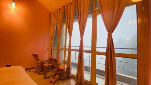 a bedroom with a large window with orange curtains at Athiti Kunj Eco Adventure Retreat in Mukteswar