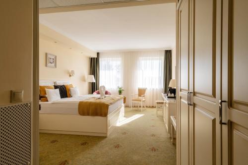 a bedroom with a bed with a child sitting on it at Calimbra Wellness Hotel Superior in Miskolctapolca