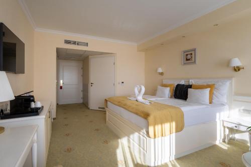 a bedroom with a large white bed with a yellow blanket at Calimbra Wellness Hotel Superior in Miskolctapolca