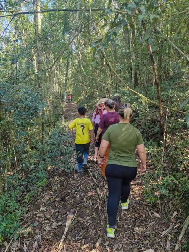 a group of people walking down a trail in the woods at Lauro Muller, Rancho Queimado in Louro Müller