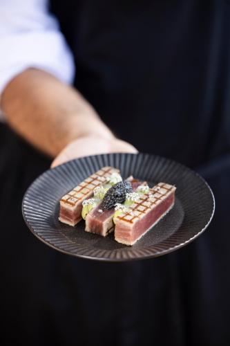 a person holding a plate with food on it at Hôtel Les Roches Blanches Cassis in Cassis